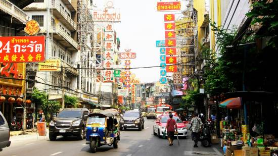Busy daytime street in Bangkok with shops and street traffic